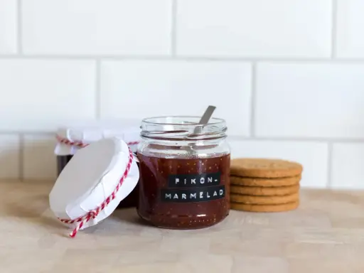 Burkar med hemlagad fikonmarmelad, perfekt för ett enkelt fikonmarmelad recept. En sked sticker upp ur den främsta burken.