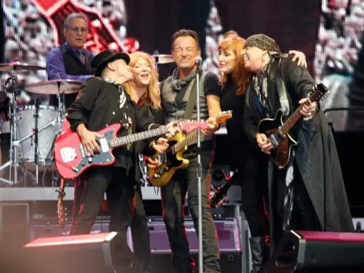 Medlemmar av E Street Band på scen, med Bruce Springsteen i mitten, omgiven av bandmedlemmar som spelar gitarr.