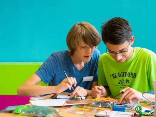 Zwei Jungen arbeiten konzentriert an einem Elektronikprojekt. Sie nutzen kreative Methoden der Gruppenarbeit, um ihre Ideen umzusetzen.