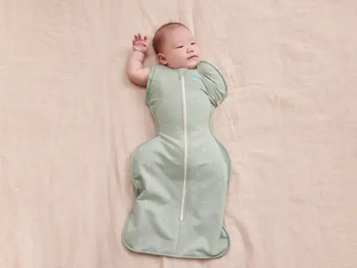 Un neonato dorme sereno, avvolto in una fascia che lo culla dolcemente.