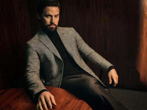 A man in a tweed blazer and dark trousers, showcasing sophisticated trouser styles.