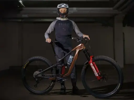 Kolarz w kasku i odzieży rowerowej prezentuje nowoczesny rower MTB. To sprzęt do ekstremalnej jazdy, a rowery mtb co to znaczy? To rowery górskie do trudnych tras.
