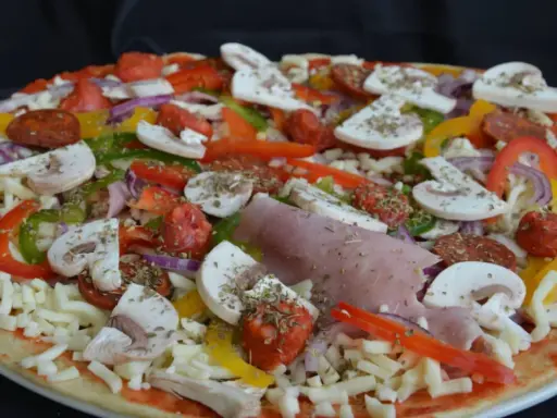 Pizza maison aux épeautre, garnie de champignons, poivrons, oignons, jambon et chorizo.