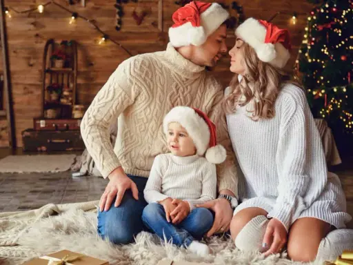 Una familia con gorros navideños, junto a un árbol de Navidad, crea una foto navidad original llena de amor y calidez.