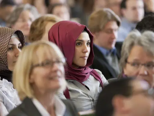 Junge Frau mit einem roten islamischen Kopftuch im Publikum.