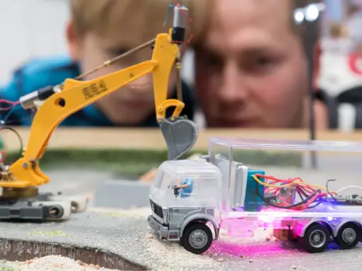 Faszination auf der **Hobby Messe Leipzig**: Ein Junge und ein Mann bestaunen eine ferngesteuerte Baustelle mit Bagger und LKW.