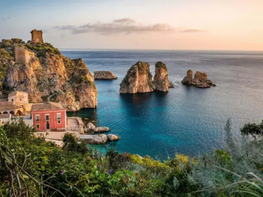 Scopri dove andare in vacanza in Italia: un borgo con torri antiche e faraglioni su un mare cristallino.