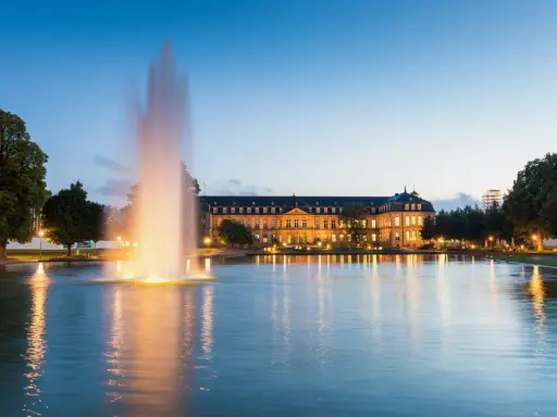 Ein beleuchteter Brunnen spiegelt sich im Wasser vor dem Neuen Schloss in der Stuttgarter Innenstadt.