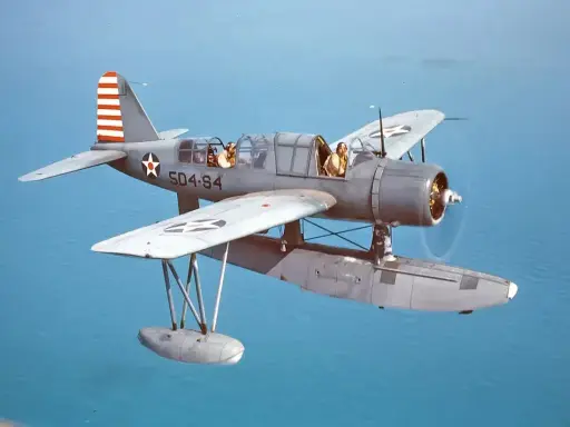 Ein Wasserflugzeug mit zwei Piloten fliegt über das Meer. Die Markierungen auf dem Flugzeug sind die von siai Marchetti.