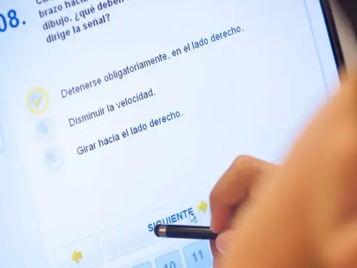 Persona haciendo un test de conducir en una tablet. La pregunta 8 es sobre una señal. ¿Cuántos test hay que hacer para aprobar el teórico?