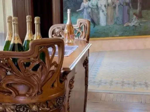 Bouteilles de champagne sur un meuble sculpté dans la maison Demoiselle à Reims. Un tableau orne le mur.