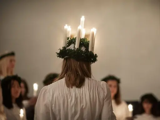 En flicka med ljuskrona bär fram ett lucia namn. Hon leder en procession av flickor med ljus i mörkret.