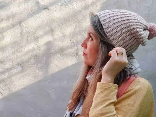 Mujer con gorro tejido a crochet, con pompón rosa. Disfruta del proceso de tejer gorros crochet.