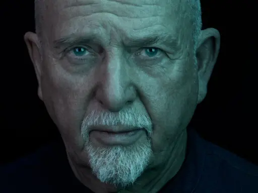 Närbild på Peter Gabriel med blå ögon och vitt skägg, ljuset ger en mystisk känsla som passar hans nya album.