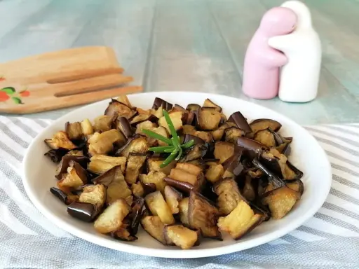 Melanzane in friggitrice ad aria, dorate e saporite, pronte per essere gustate. Un rametto di rosmarino le impreziosisce.