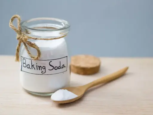 Słoik z napisem "Baking Soda" i drewniana łyżka z proszkiem. To naturalny sposób na usuwanie plam.