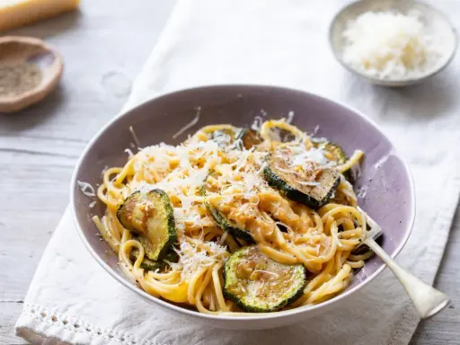 Pyszny makaron z cukinią i pieczarkami, posypany parmezanem. Idealny lekki obiad.
