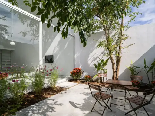 Un patio moderno con mesa y sillas de madera, flores y un árbol. ¡Excelentes ideas para porches pequeños y acogedores!