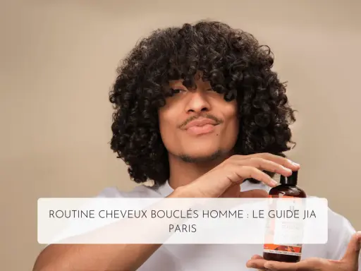 Un homme aux cheveux bouclés tient un flacon de shampoing, parfait pour l'hydratation cheveux bouclés.