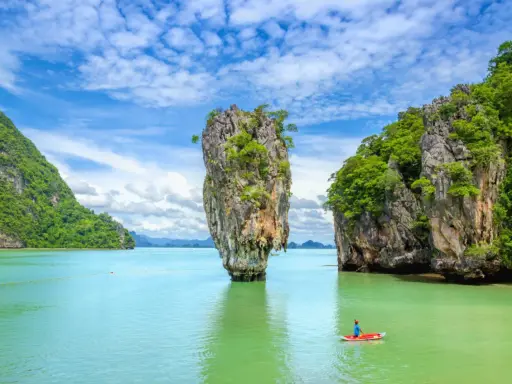 Wyspa Phuket, Tajlandia: samotna skała wyrasta z turkusowej wody, a kajakarz podziwia krajobraz.