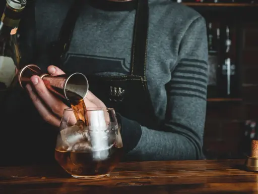 Barman nalewa whisky Glenlivet 12 do szklanki z lodem. Wiele pozytywnych opinii potwierdza jej jakość.