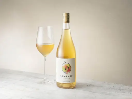 En flaska och ett glas med gyllene Semente Avesso vin.