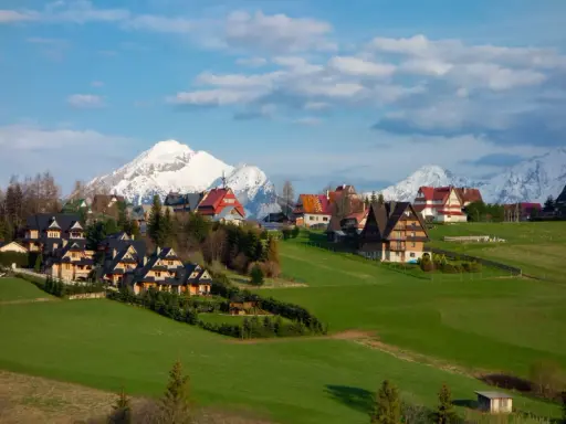 Malownicze domy w Murzasichlu z widokiem na ośnieżone Tatry. Atrakcje tego miejsca to przede wszystkim piękno przyrody i spokój.