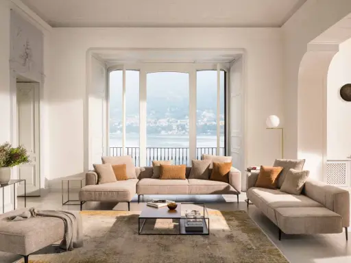 Un salon blanc et beige cocooning, avec des canapés confortables, un tapis doux et une vue imprenable sur un lac.