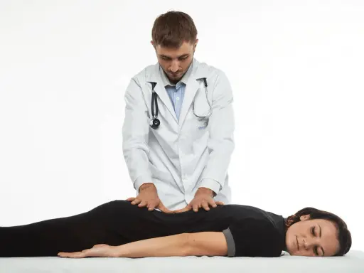 Terapeuta wykonuje delikatne ruchy na plecach pacjentki, co ilustruje, na czym polega terapia Bowen'a.
