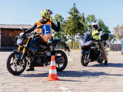 Nauka jazdy na motocyklu. Kursant w kamizelce z literą "L" i kasku na motocyklu, gotowy do zdobycia prawko na motocykl.