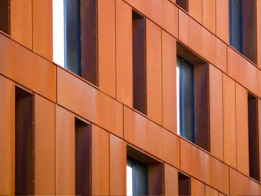 Fachada de edificio revestida con paneles de acero corten, creando un efecto oxidado y moderno.