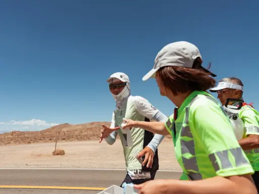 Läufer beim Badwater 135 Ultra-Marathon in der Wüste. Eine Helferin reicht einem Läufer Wasser.
