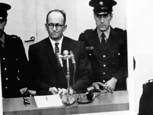 Adolf Eichmann w szklanej kabinie, otoczony strażnikami. Jego proces był transmitowany na cały świat, budząc grozę i pytania o losy dzieci.