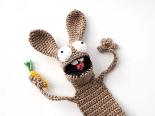Un divertido conejo amigurumi de crochet, con ojos saltones y una zanahoria en la mano, parece listo para una aventura.
