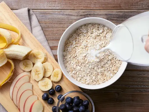 Haferflocken mit Milch, geschnittener Banane, Äpfeln und Blaubeeren. Eine gesunde Mahlzeit, die hilft, Cholesterin zu senken.