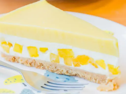 Pyszny sernik mango z kawałkami owoców i kremową warstwą na kruchym spodzie.