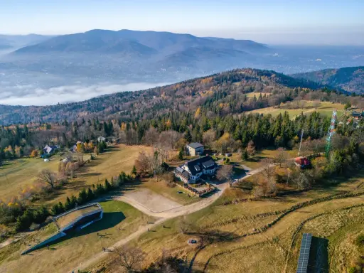 Widok z lotu ptaka na górski krajobraz jesienią. Widać budynki, lasy i dolinę z mgłą. Taki widok to prawdziwy przegibek!