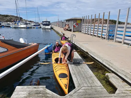 Förberedelser för kajakpaddling i Lysekil. En gul kajak ligger i vattnet vid en brygga, redo för äventyr.