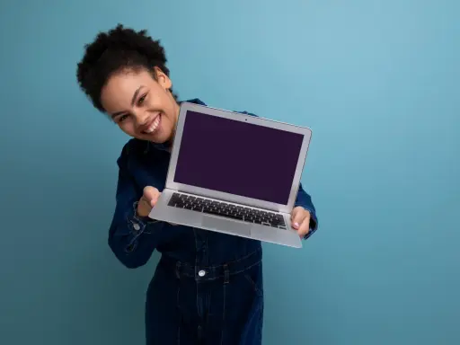 Uśmiechnięta kobieta prezentuje laptopa, gotowa do sprzedaży. Dowiedz się, jak przygotować laptop do sprzedaży, by uzyskać najlepszą cenę.