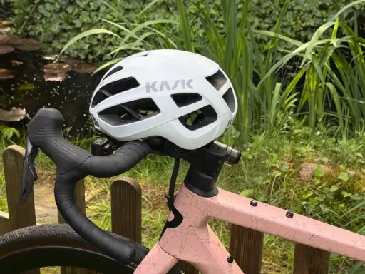 Biały kask rowerowy KASK na kierownicy różowego roweru. Przygotowany do jazdy, zgodnie z przepisami ruchu drogowego dla rowerzystów.