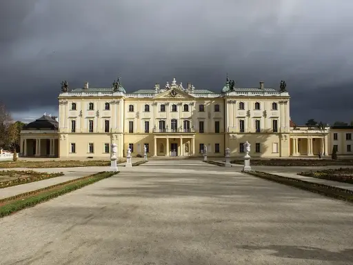 Pałac Branickich w Białymstoku, majestatyczna budowla z ogrodem, pod burzowym niebem.