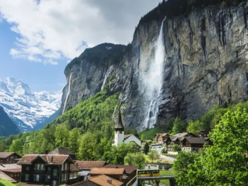 Lauterbrunnen Wasserfall stürzt von einer Felswand, umgeben von einem Dorf und schneebedeckten Bergen.
