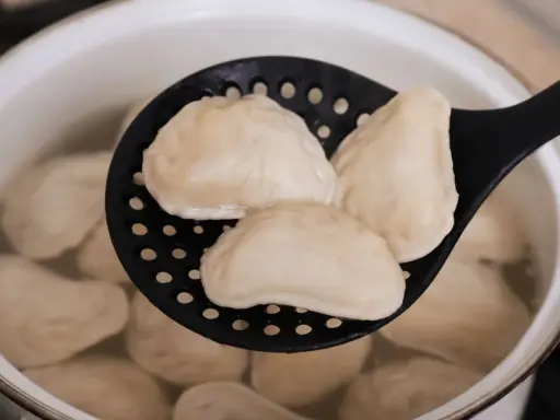 Gotowanie mrożonych pierogów: wyjęte z wrzątku na cedzaku, gotowe do podania.