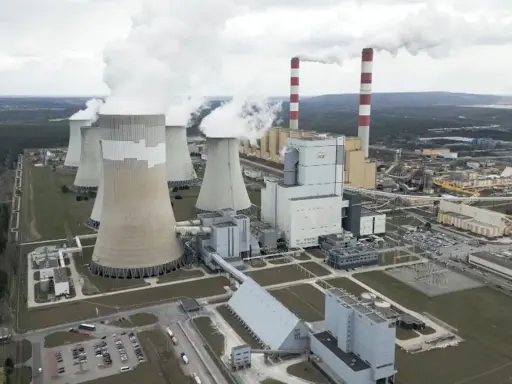 Große Kühltürme und Schornsteine einer polnischen Kraftwerksanlage, die Dampf abgeben. Der Strommix Polens wird hier sichtbar.