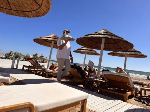 Kellnerin bringt Getränke an Liegestühle am Strand. Perfekte Feiertage Spanien!