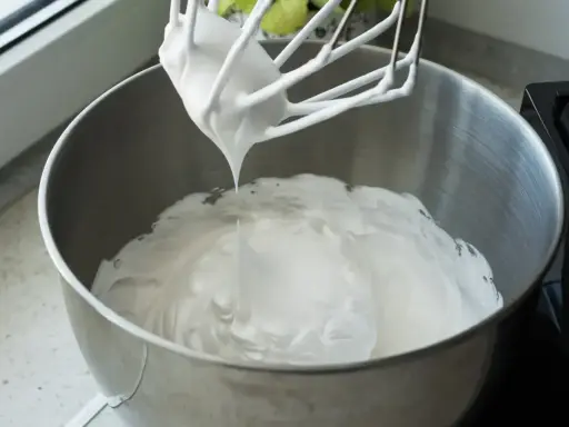 Ubita masa z mascarpone i białek, gotowa do przygotowania pysznego ciasta bez pieczenia.