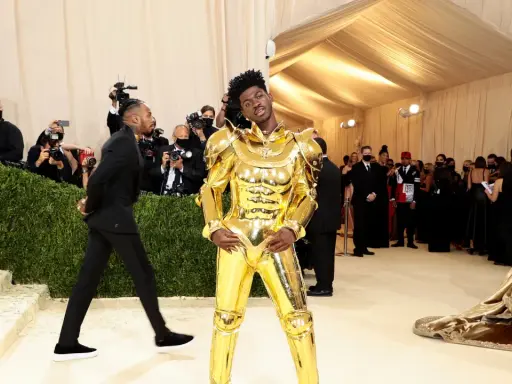 Lil Nas X, un caballero dorado, posa en la alfombra de la Met Gala, rodeado de fotógrafos y admiradores.
