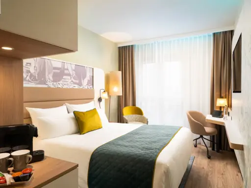 Modern Hotelzimmer mit Bett, Schreibtisch und Kaffeemaschine.