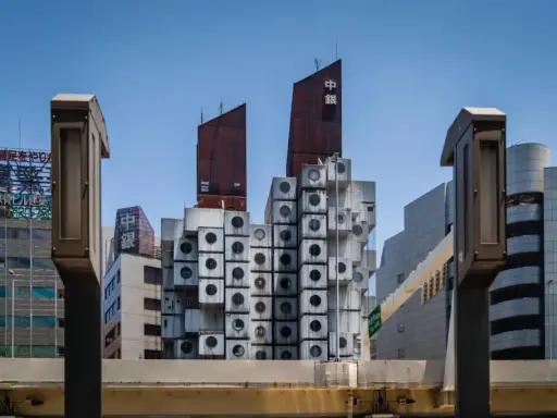 Iconica Nakagin Capsule Tower, un capolavoro di architettura modulare con capsule cubiche impilate, si staglia contro il cielo azzurro.
