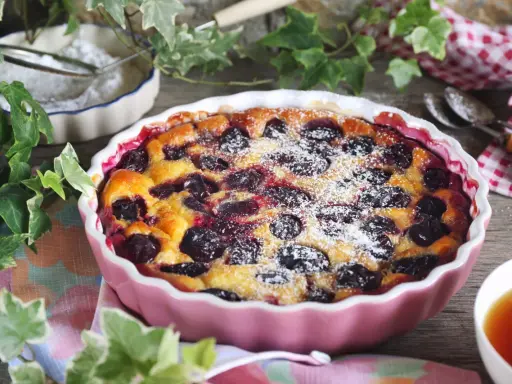 Un délicieux clafoutis aux prunes, saupoudré de sucre glace, prêt à être dégusté.